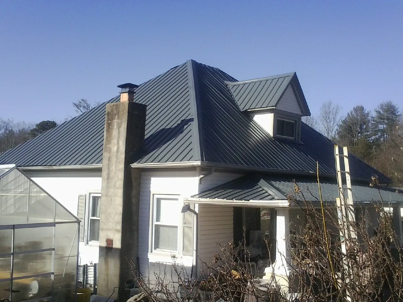 Dark blue standing seam metal roof on a white farmhouse with dormer — Slate & Tile Roof Repair by Roofing Brothers in Mc Caysville