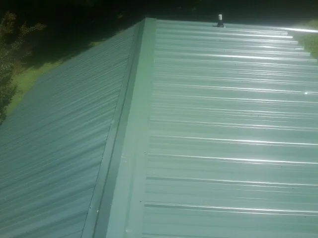 New green metal panels meeting at the ridge of a roof — Flat Roof Repair work by our crew in Mc Caysville