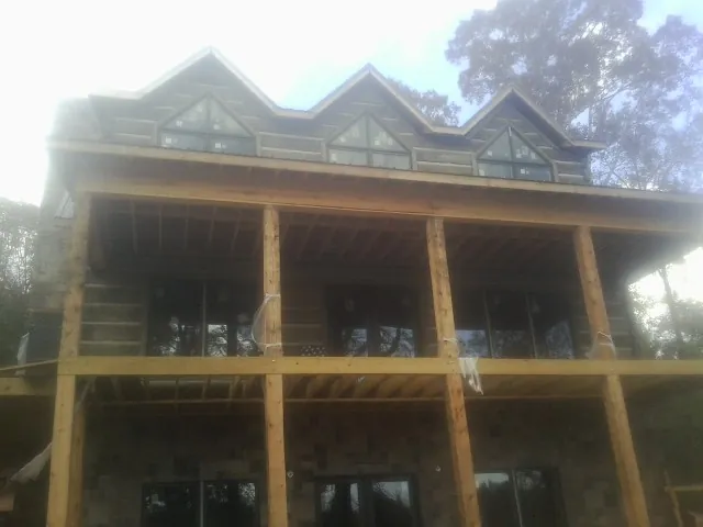 Dormers and porch framing on a large log home under construction — Roof Coating work by our crew in Mc Caysville