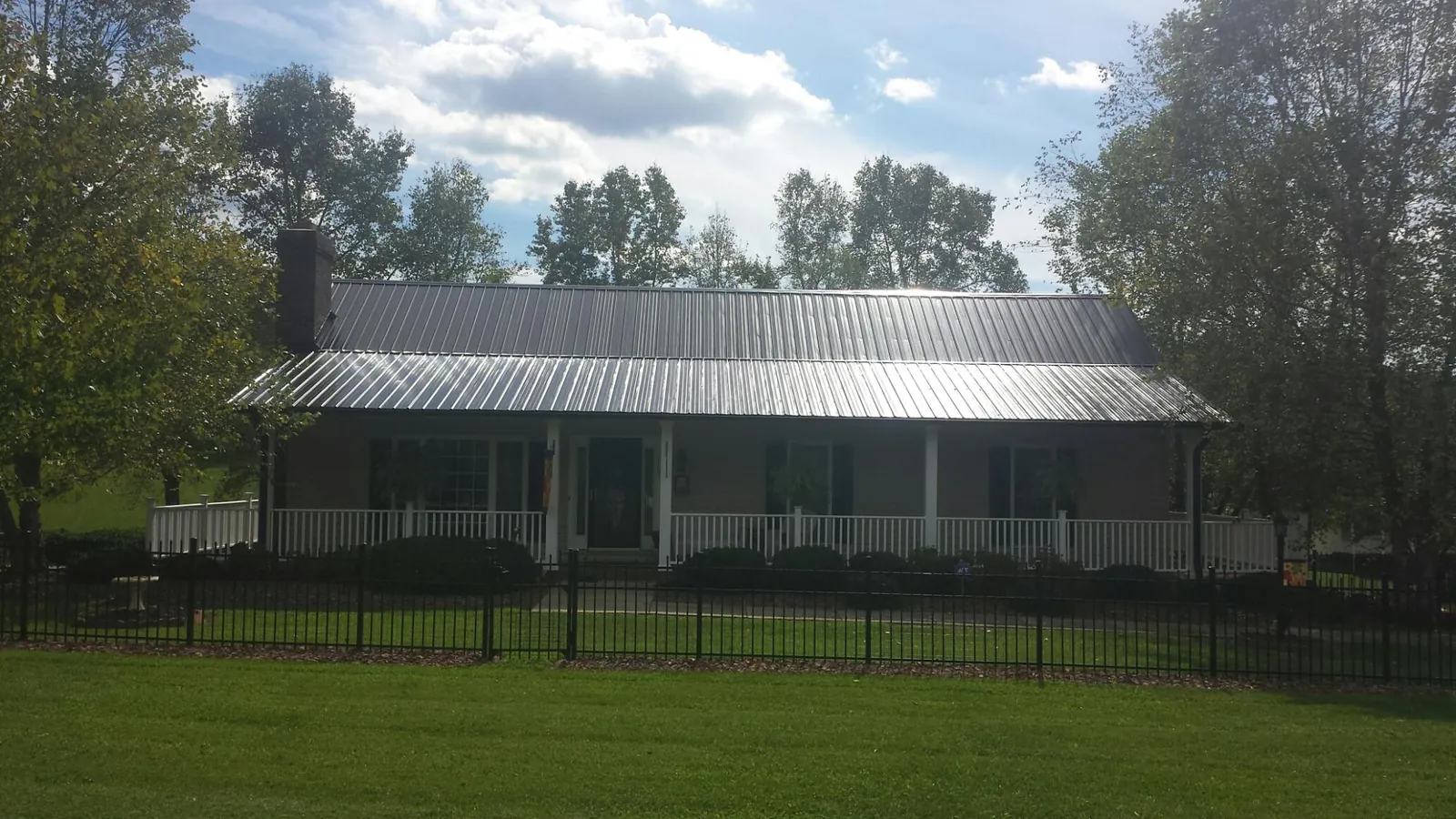 Gray metal roof on a brick ranch with a full width front porch — Gutter Guard Installation work by our crew in Mc Caysville