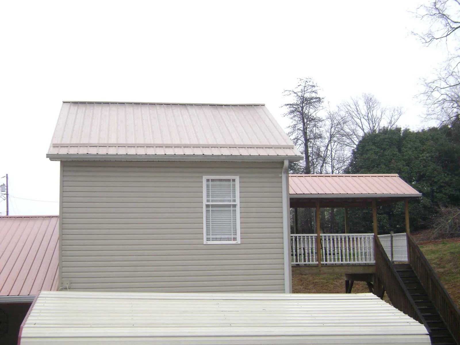 Tan metal roofs on a two story addition and attached porch, from a Roof Replacement job in Mc Caysville