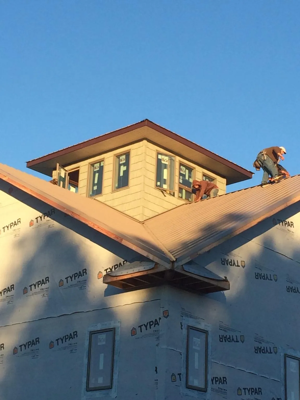 Roofers working around a rooftop cupola on a new metal roof at sunset — Roof Waterproofing in Mc Caysville by Roofing Brothers